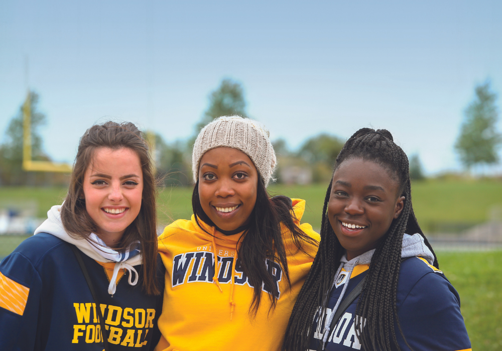 3 students standing side by side and wearing uwindsor hoodies