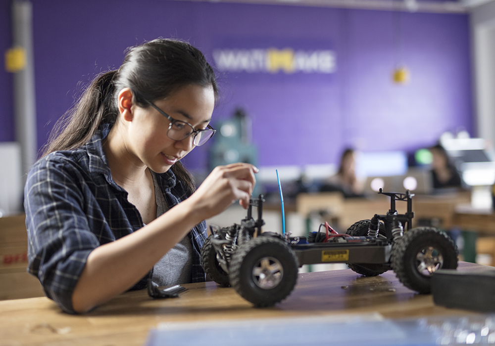 Engineering student working on a test car in robotics lab