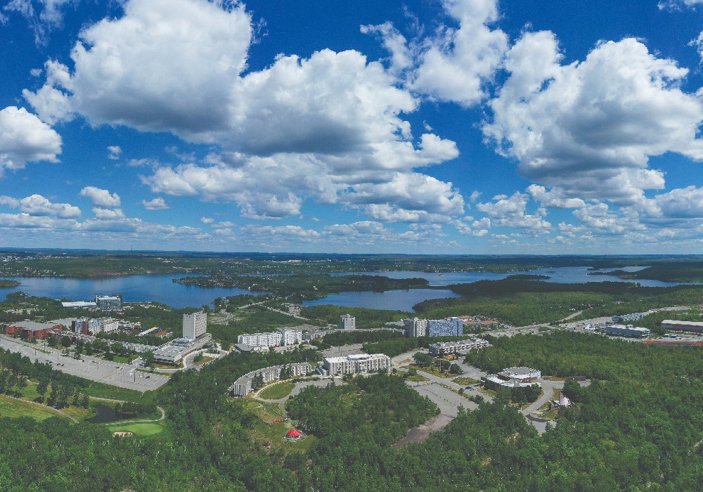 Trois étudiants internationaux de la Laurentienne prenant un selfie devant le Big Nickel de Sudbury.