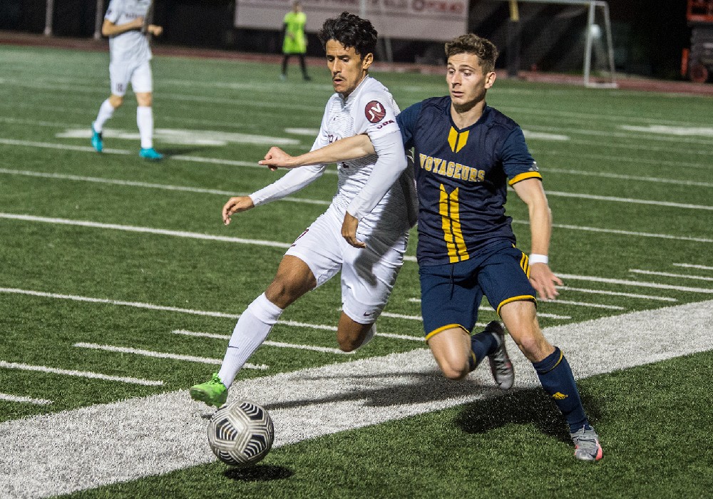A Laurentian University varsity soccer player going after the ball in a soccer match.