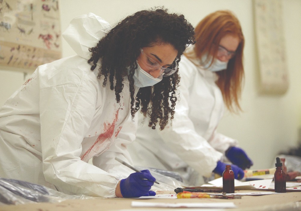 Deux étudiants de la Laurentienne utilisent des pinceaux et de la peinture pour créer une image sur une toile.