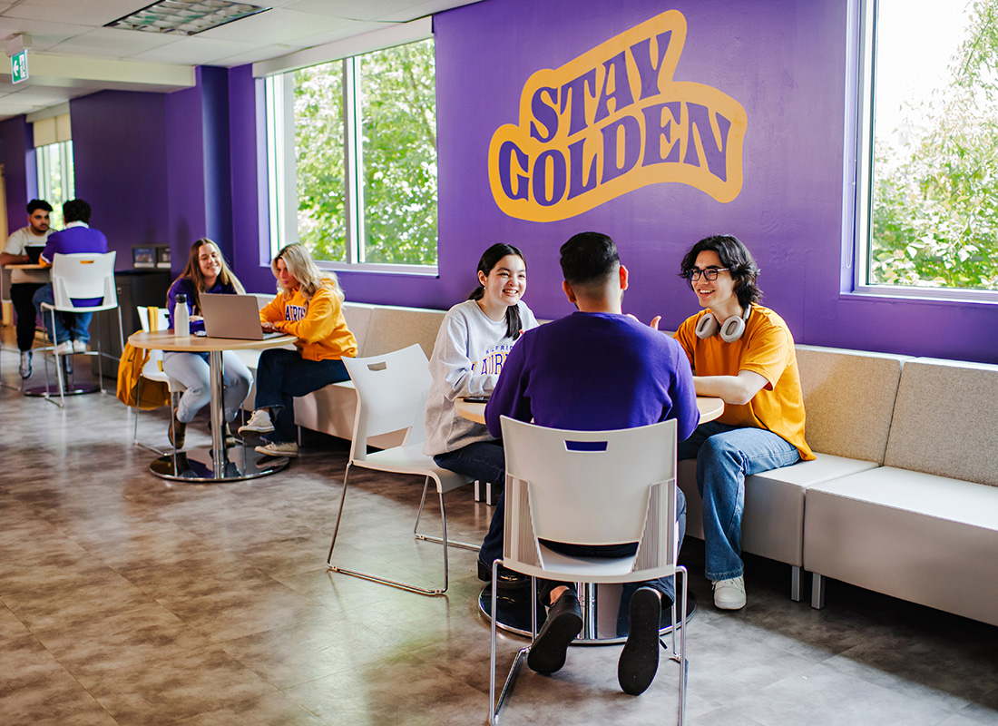 Students sitting at a table in front of a Stay Golden sign